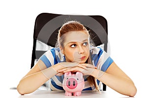 Teenage woman with piggybank on the table