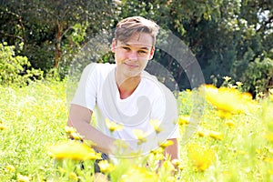 A teenage young boy is having fun in a field of chrysanthemum