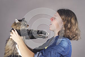 A teenaged allergic girl holds a maine coon cat