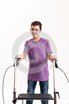 Teenaged disabled boy with cerebral palsy in the glasses smiling at camera, taking steps with his walker isolated over