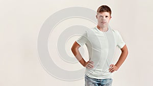 Teenaged disabled boy with Down syndrome looking at camera while posing, standing with hands on waist isolated over