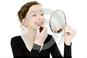 Teenaged girl in black dress making make up in mirror - lipstick