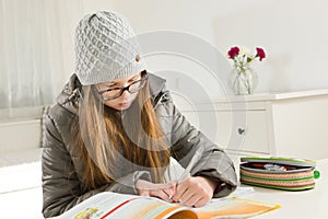 Teenaged girl going homework in hard condition - heating is not working during winter time