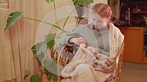 Teenaged girl knits sitting in an armchair near window. Evening soft light. Handmade things