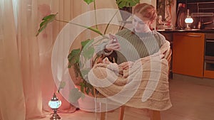 Teenaged girl knits sitting in an armchair near window. Evening soft light. Handmade things