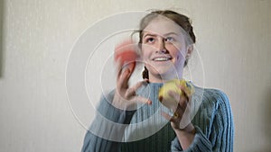 A teenaged girl plays with yarn balls and juggke with them near white wall.