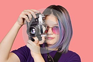 Teenager asian girl with old school photo camera against vibrant pink background. Youthful enthusiasm for photography