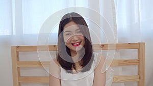 Teenager Asian woman feeling happy smiling and looking to camera while relax in bedroom at home. Lifestyle beautiful Asian young