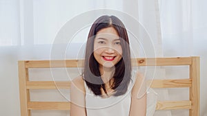 Teenager Asian woman feeling happy smiling and looking to camera while relax in bedroom at home. Lifestyle beautiful Asian young