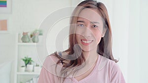 Teenager Asian woman feeling happy smiling and looking to camera while relax in her bedroom at home.