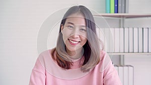 Teenager Asian woman feeling happy smiling and looking to camera while relax in her living room at home.