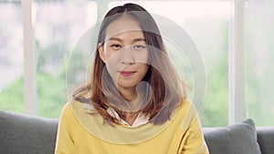 Teenager Asian woman feeling happy smiling and looking to camera while relax in her living room at home.