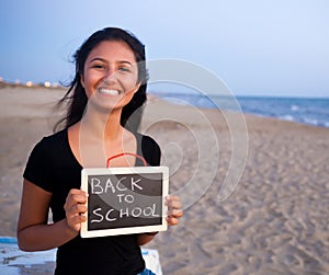 Teenager with blackboard on the beach. Concept of back to school