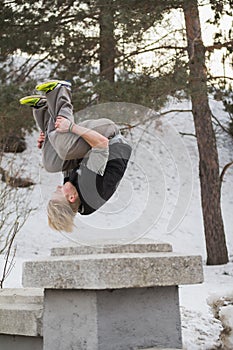 Teenager blonde hair man training parkour jump in the snow covered park photo