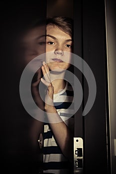 Teenager boy behind ajar door