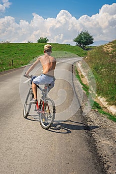 Teenager boy on bicycle on the road outside the city in nature