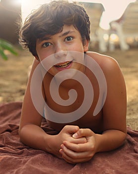 Teenager boy with brown tan having sun bath on the beach photo