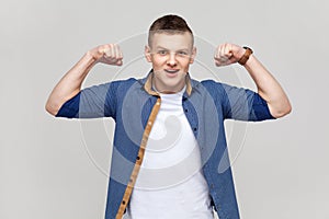 Teenager boy demonstrating power in his hands, showing biceps, feeling energy to win success.