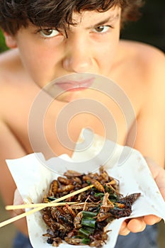 Teenager boy with disgust grimace hold unusial strange thai food
