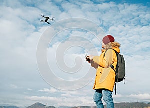 Teenager boy dressed yellow jacket piloting a modern digital drone using remote controller