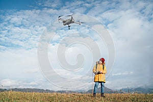 Teenager boy dressed yellow jacket piloting a modern digital drone using remote controller