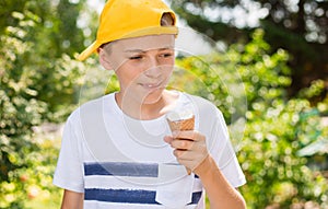 Teenager boy eating ice-cream cone on green nature background. Summer, junk food and people concept