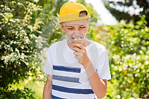 Teenager boy eating ice-cream cone on green nature background. Summer, junk food and people concept