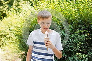 Teenager boy eating ice-cream cone on green nature background. Summer, junk food and people concept