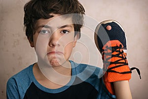 Teenager boy frustrated about hole in his favourite trainers shoes