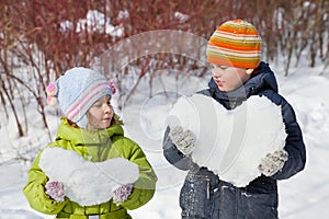 Teenager boy and girl keep hearts from snow
