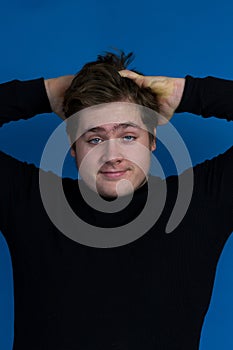 Teenager boy with goofy expression messing his thick light brown hair