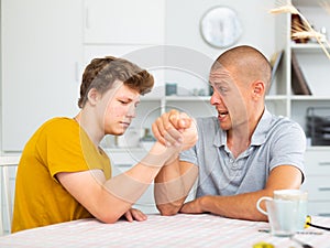 Teenager boy and his father arm wrestling