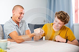 Teenager boy and his father arm wrestling