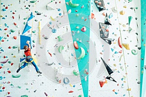 Teenager boy at indoor climbing wall hall. Boy is climbing using an auto belay system and climbing harness. Active teenager time photo