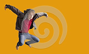 Teenager boy jumping dance movement on a colored yellow background