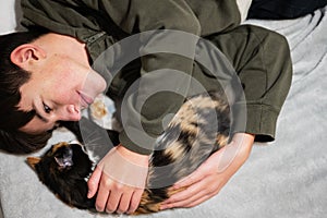 Teenager boy with kitty lying on the sofa. Children`s love for pets