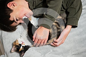 Teenager boy with kitty lying on the sofa. Children`s love for pets