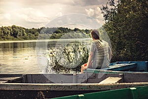 Teenager boy lonely contemplation countryside scenery on river boat during countryside summer holidays