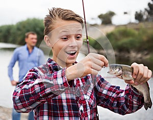 Teenager boy looking at fish on hook