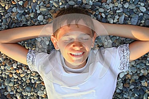 Teenager boy lying on stones, closed eyes