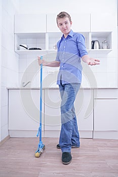 Teenager Boy Mopping The Floor and helps his parents to clean on kitchen