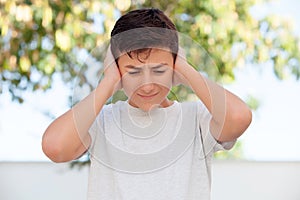 Teenager boy outdoor covering his ears