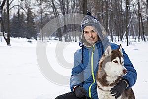 Teenager boy plaing with white Husky dog in winter day