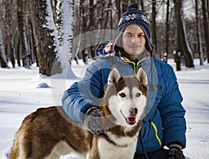Teenager boy playing with white Husky dog in winter day, dog and child on snow