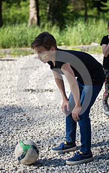 Teenager boy playing in yard football preparing to kick the ball