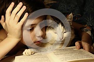 Teenager boy reading book in bed with sleeping cat