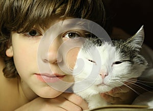 Teenager boy reading book with cat in bed