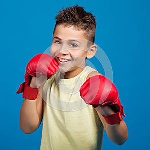 Teenager boy, in red gloves for karate or kickboxing, stands in a rack and smiles, concept