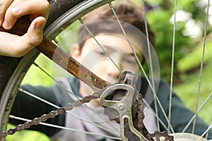 Teenager boy repair bicycle tire close up summer photo