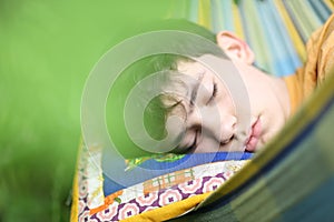 Teenager boy resting sleep with book in hammock on summer green garden